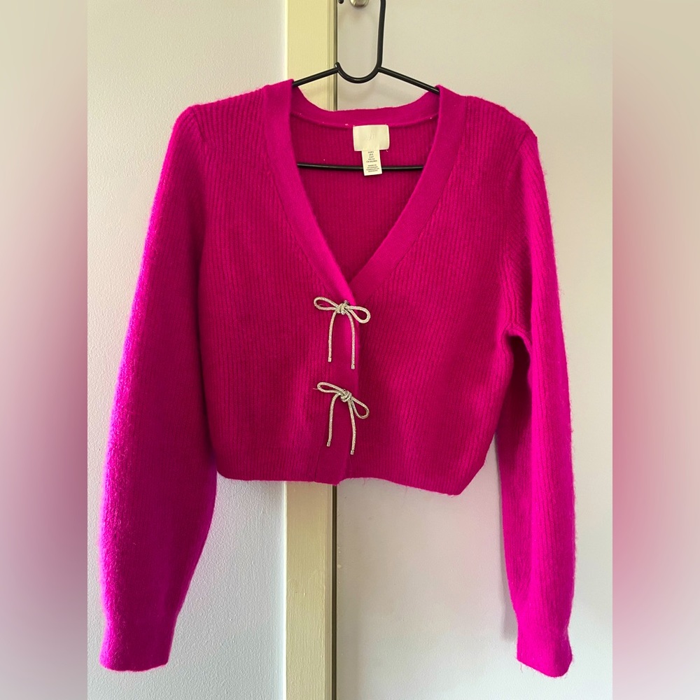 Fuchsia sweater with rhinestone bow buttons.